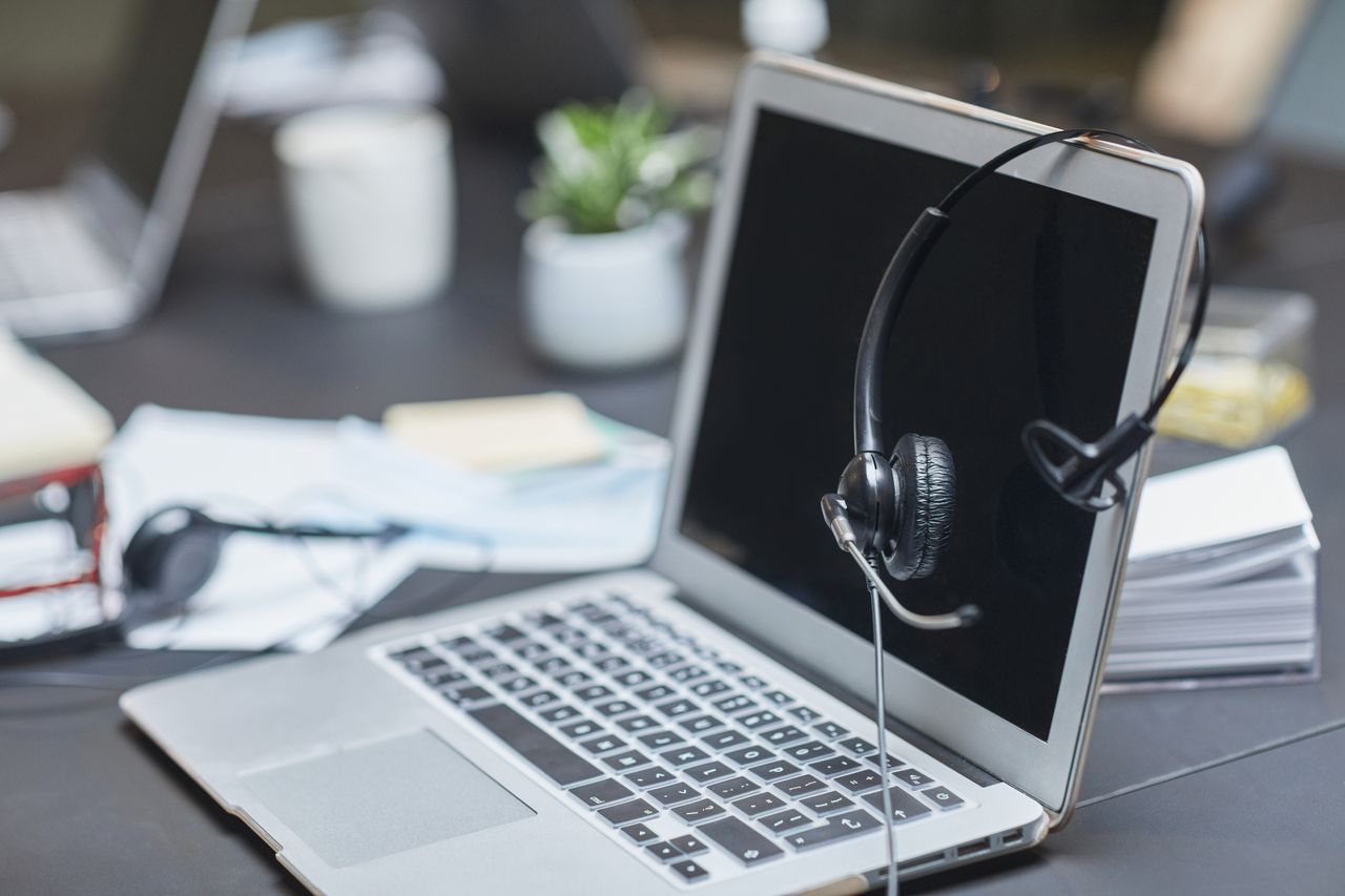 The Art of Drawing Readers In: Your attractive post title goes here A headset placed on a laptop in a modern, cluttered office setting with papers and plants.